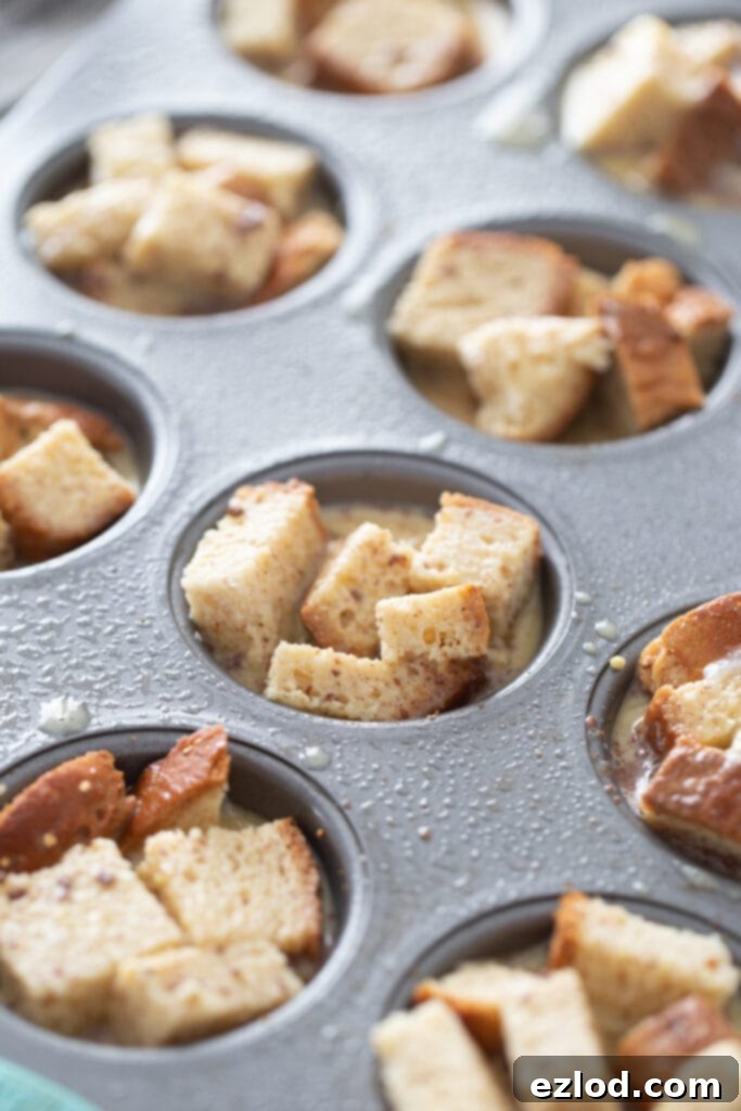 Bread cubes are perfectly portioned into individual cupcake tins, ready to be soaked in the egg mixture.