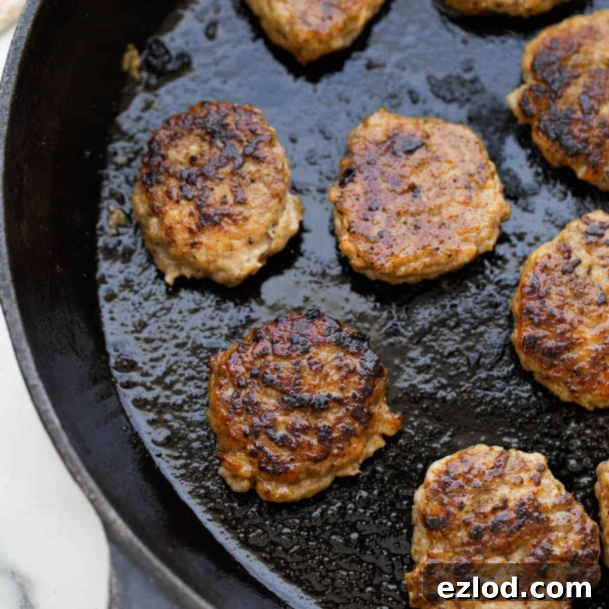 Homemade Maple Chicken Breakfast Sausages 2 A cast iron skillet with homemade chicken sausage patties cooked golden brown, ready to be served for breakfast.