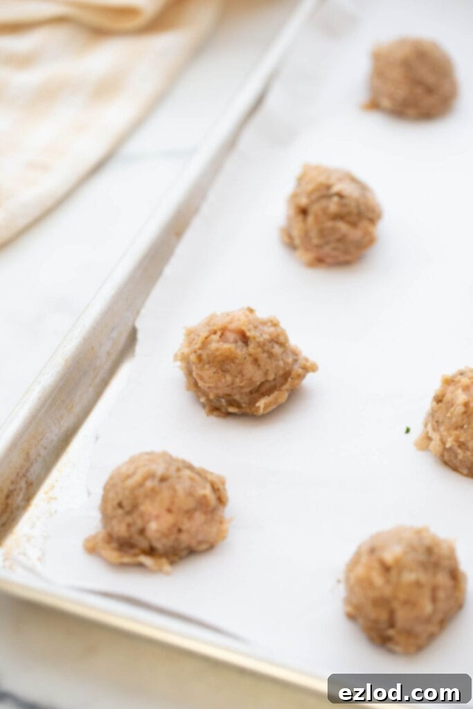Homemade Maple Chicken Breakfast Sausages 6 Scoops of ground chicken sausage mixture shaped into small balls on parchment paper.