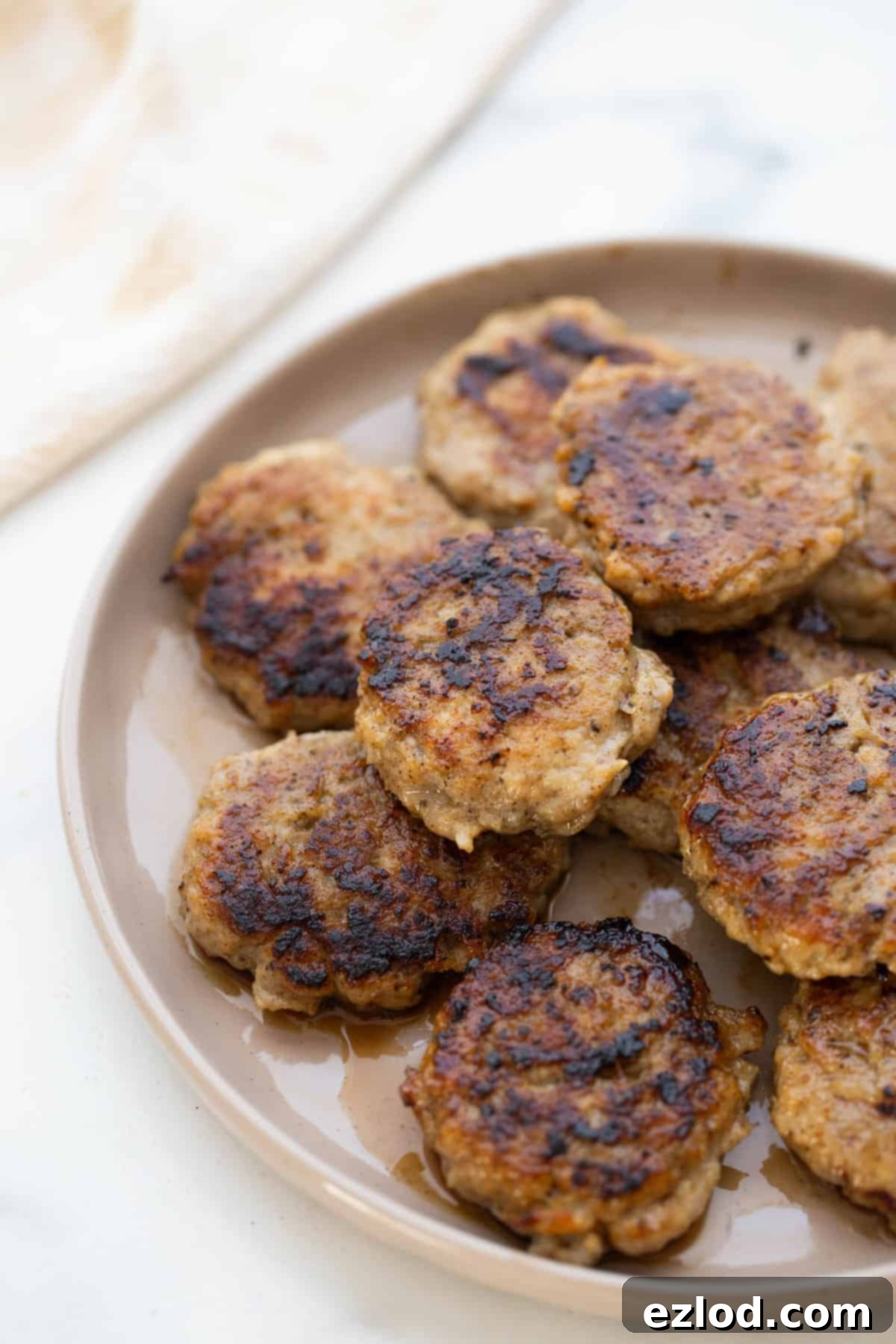 Homemade Maple Chicken Breakfast Sausages 8 A plate of freshly cooked, golden-brown chicken breakfast sausage patties, ready to eat.