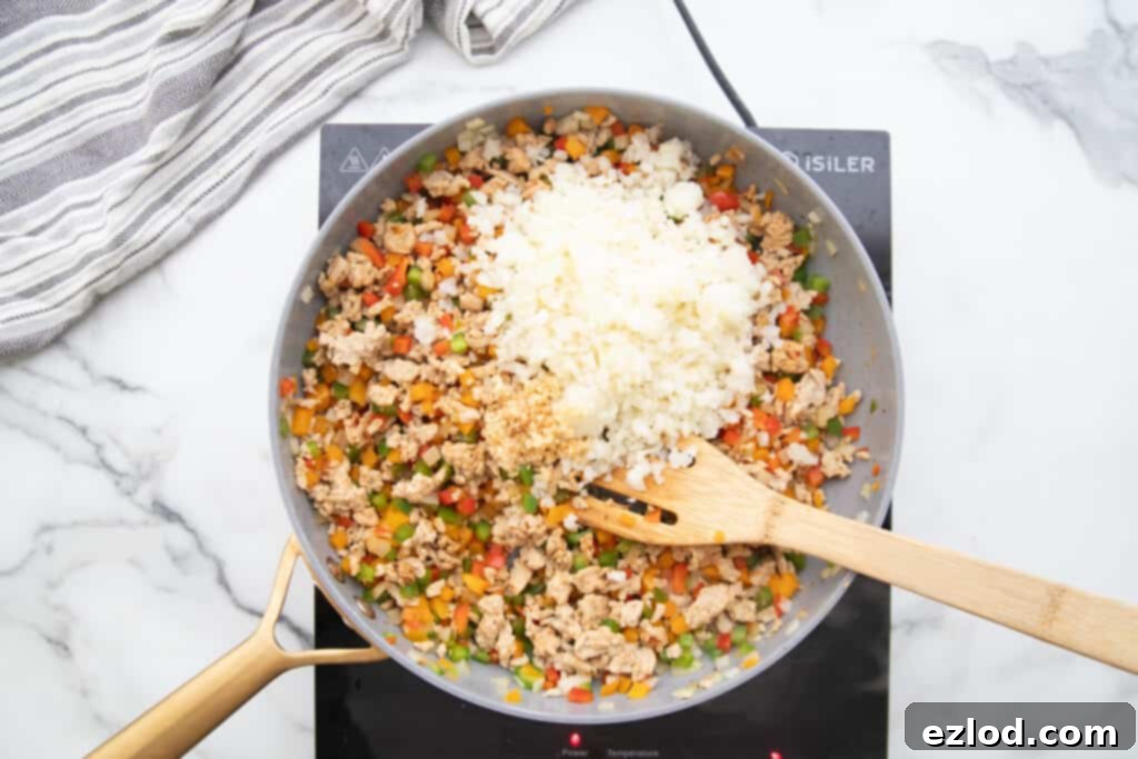 Skillet with ground chicken, peppers, and cauliflower rice.