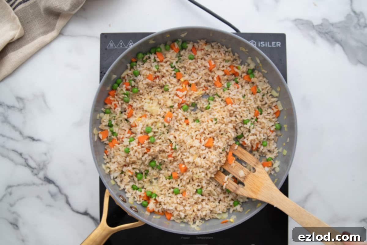 Wholesome Gluten-Free Hibachi Fried Rice 6 Day-old brown rice being added to a hot skillet with butter and avocado oil, ready to be fried for a crispy texture.
