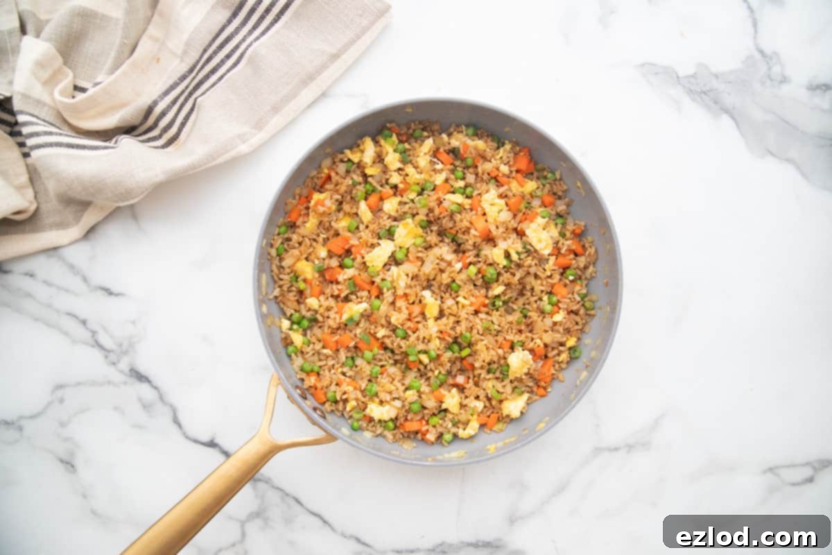 Wholesome Gluten-Free Hibachi Fried Rice 8 A non-stick skillet brimming with healthy hibachi fried rice, featuring golden brown rice, colorful fresh vegetables, and scrambled eggs, ready to be served.