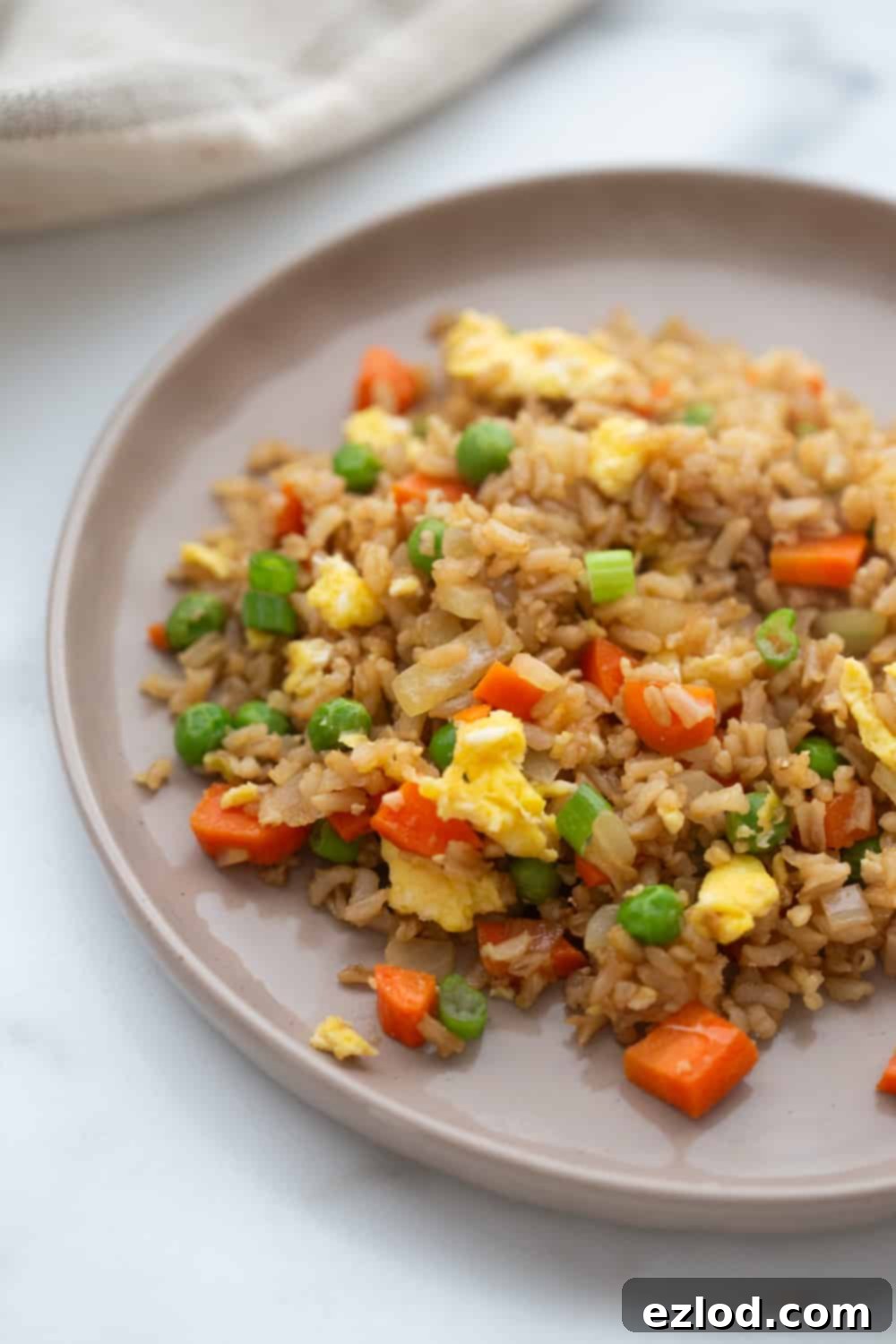 Wholesome Gluten-Free Hibachi Fried Rice 9 A beautifully plated serving of healthier copycat hibachi fried rice on a white rimmed plate, garnished with green onions.