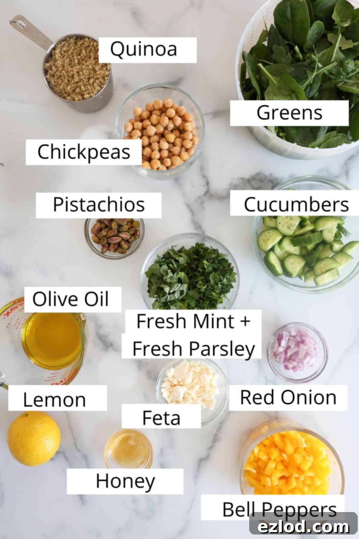 Ingredients with labels for the Jennifer Aniston salad, showing fresh produce, quinoa, chickpeas, feta, and pistachios.