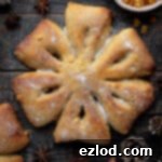 Orange and anise snowflake bread on a wooden background surrounded by Christmas decorations and a bowl of candied peel.