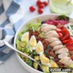 A vibrant bowl of homemade Copycat Panera Green Goddess Cobb Salad ingredients including chicken, bacon, eggs, avocado, and greens, ready to be dressed.