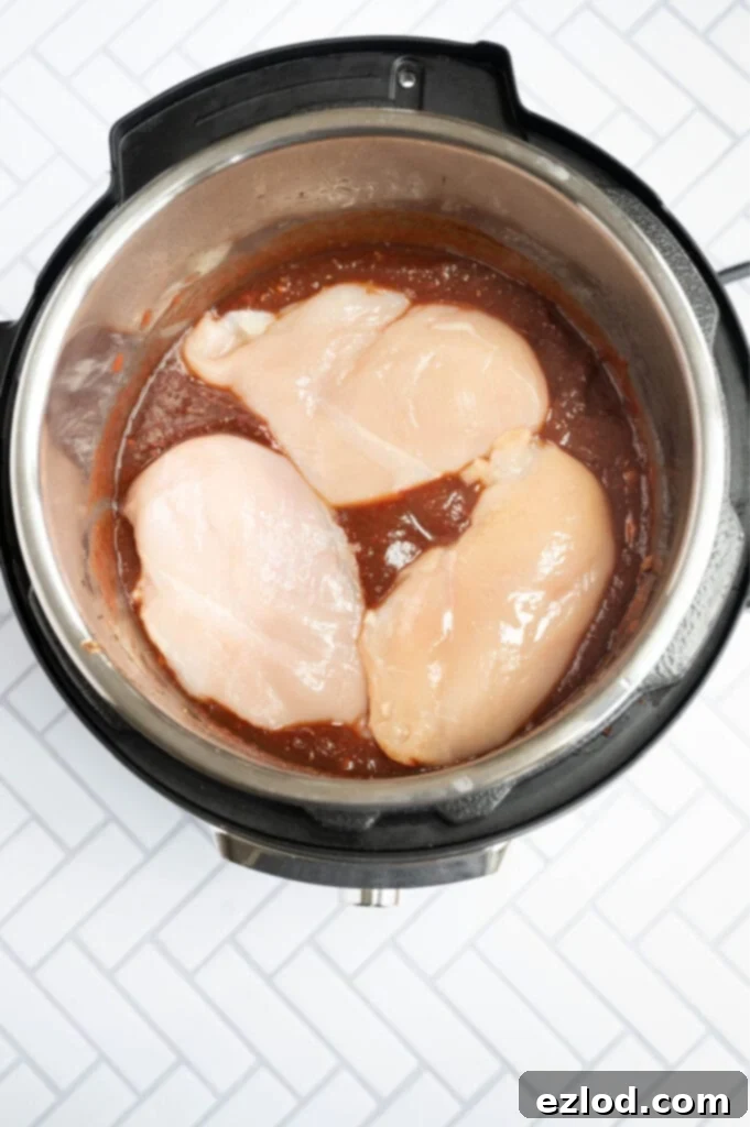 Overhead photo of an Instant Pot full of balsamic chicken ingredients, including chicken on the top.