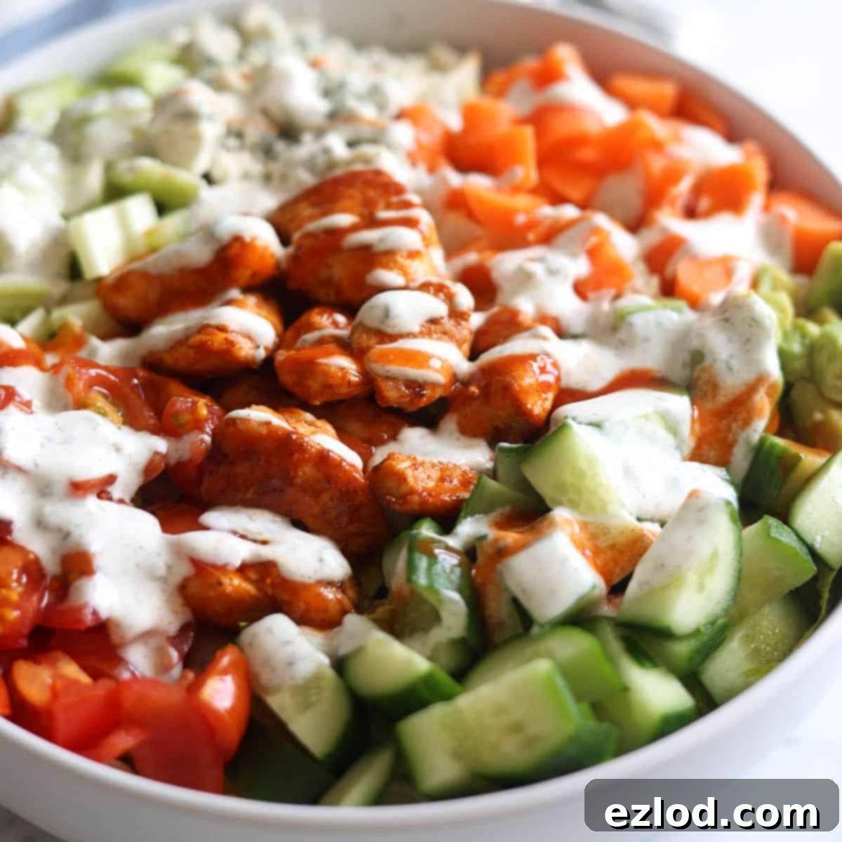 Close up photo of restaurant style buffalo chicken salad topped with a healthy greek yogurt ranch.