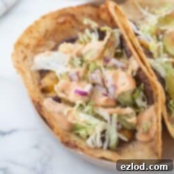 Gluten-free Big Mac tacos topped with lettuce, Big Mac sauce, pickles and onions.