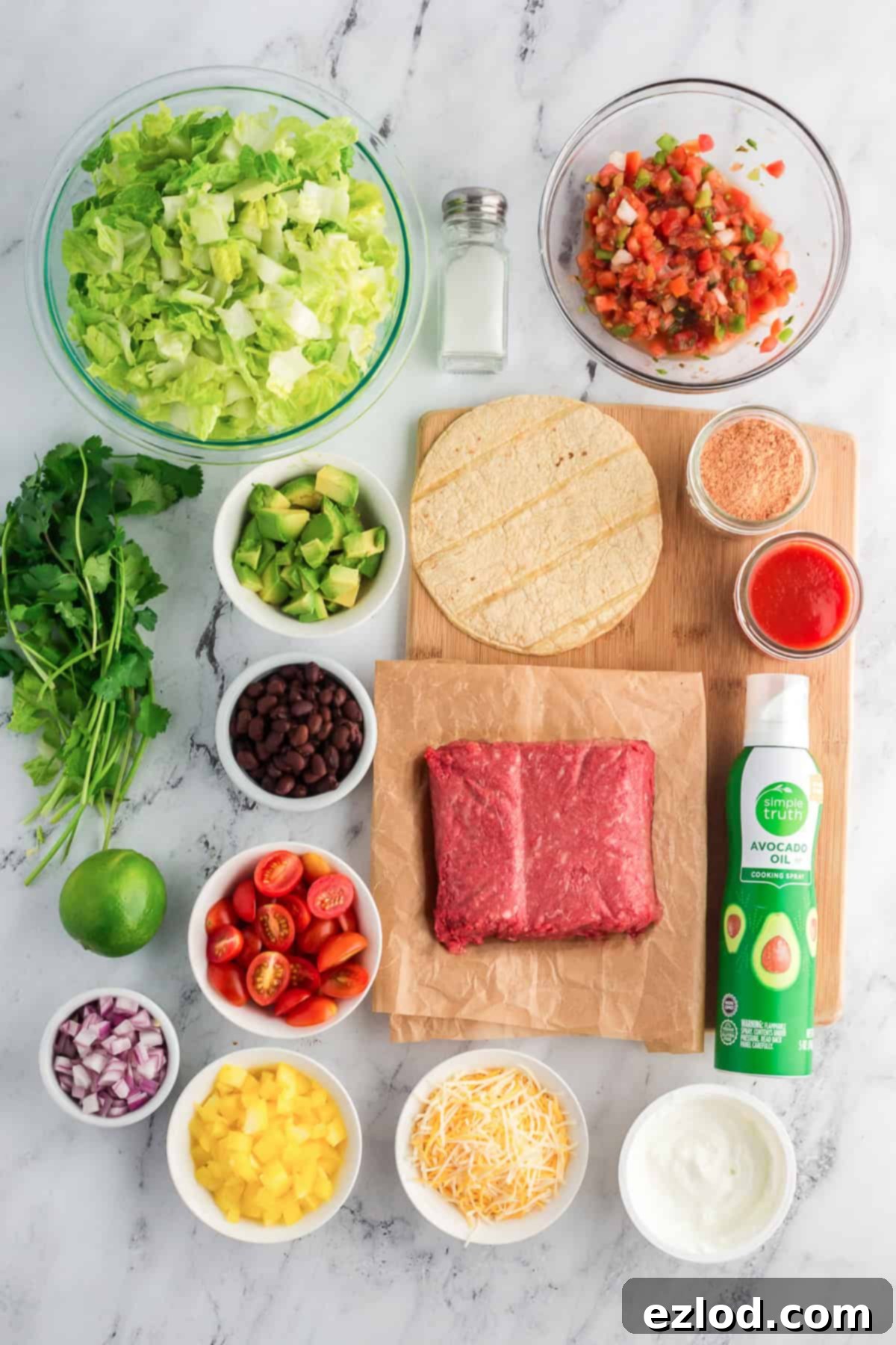Our Favorite Simple and Healthy Taco Salad Recipe 4 Ingredients laid out for a healthy taco salad, including ground meat, fresh vegetables, and spices.