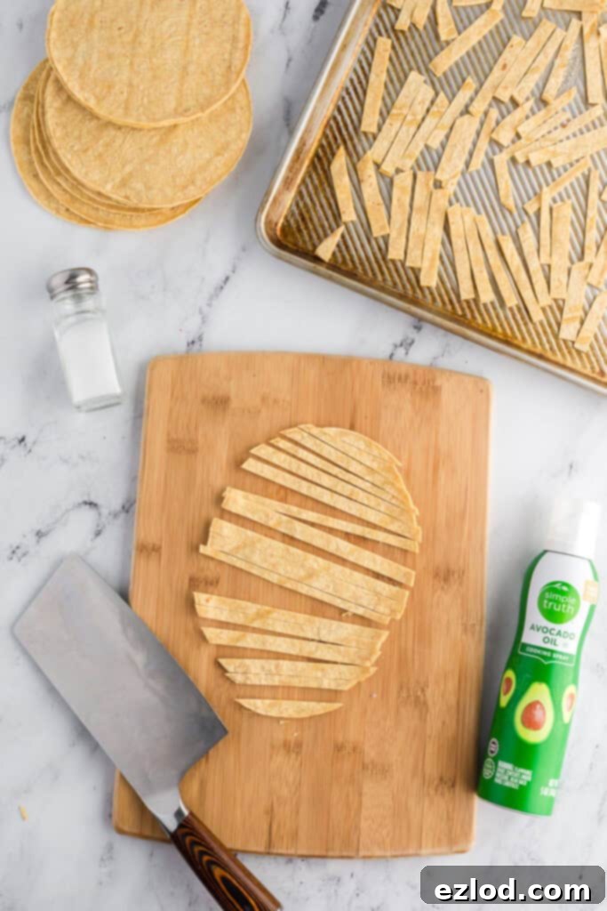 Our Favorite Simple and Healthy Taco Salad Recipe 5 Corn tortillas cut into strips on a wooden cutting board, ready for baking.