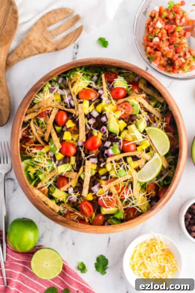 Our Favorite Simple and Healthy Taco Salad Recipe 7 Healthy Taco Salads in wooden bowls, topped with various fresh ingredients like avocado, cheese, and lime.