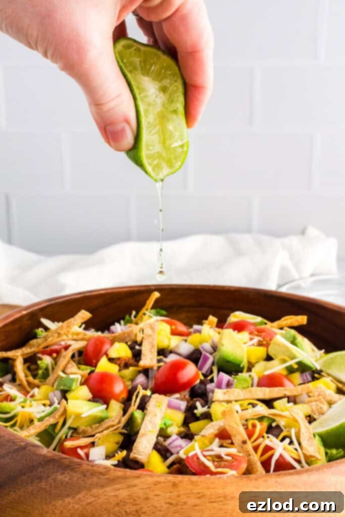 Our Favorite Simple and Healthy Taco Salad Recipe 9 A lime being squeezed over a homemade taco salad, adding a fresh burst of flavor.