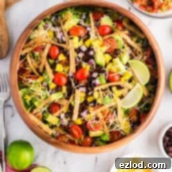 Our Favorite Simple and Healthy Taco Salad Recipe 10 Healthy Taco Salads in a wooden bowl topped with tortilla strips, cheese, avocado, and fresh lime.