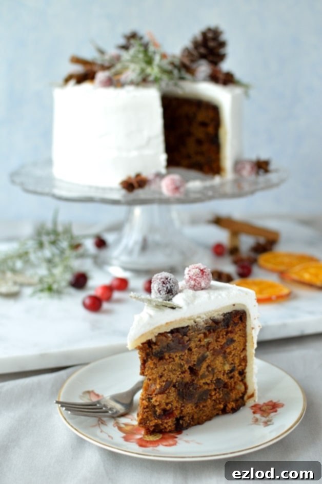 Gingered Christmas fruitcake with royal icing, pine cones, dried orange slices, spices and sugared cranberries, rosemary and bay leaves