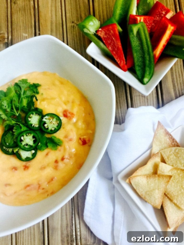 Creamy 21 Day Fix Queso Dip served with homemade tortilla chips on a rustic wooden board.