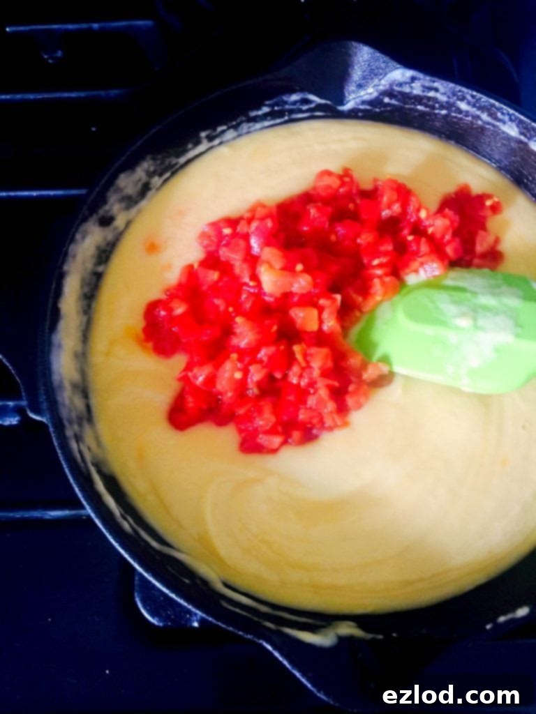 Close-up of a homemade tortilla chip scooping up a generous amount of the healthy cauliflower queso dip.