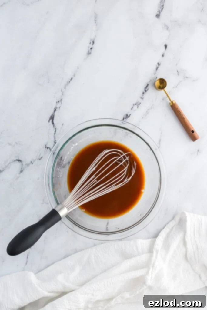 Homemade bourbon sauce ingredients being whisked together in a bowl before adding to chicken.