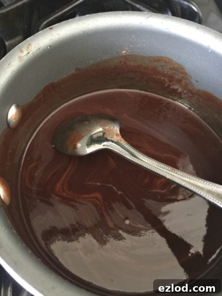 Dairy Free chocolate fondue recipe in a pot on the stove with a spoon turned over in the pot