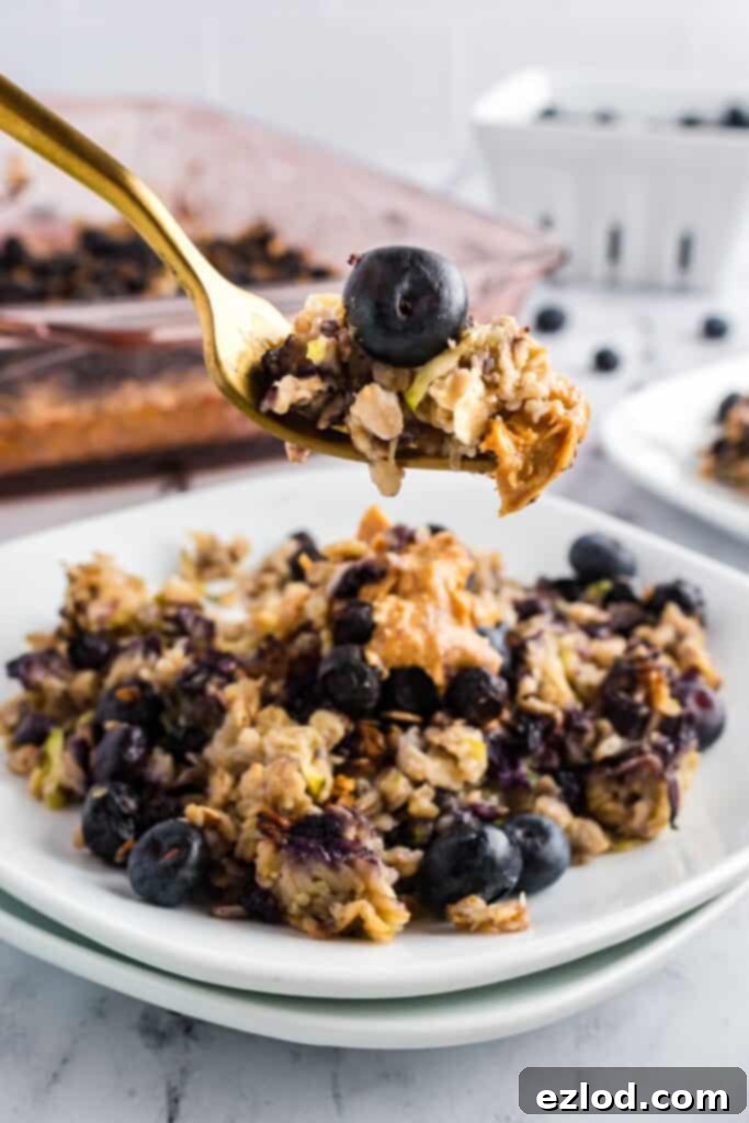 A bite shot of of zucchini blueberry baked oatmeal on a double stacked white plate.