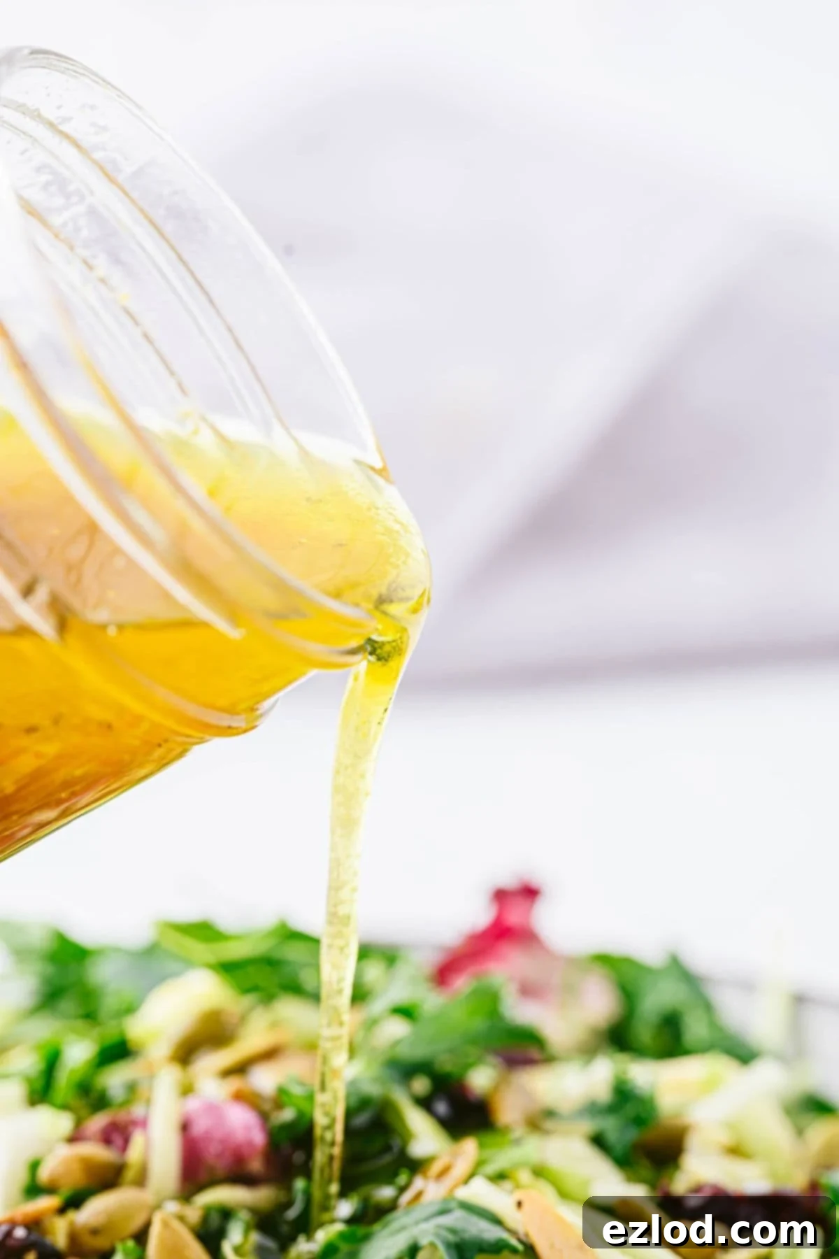 Close-up of apple cider vinaigrette being poured over a fall salad.