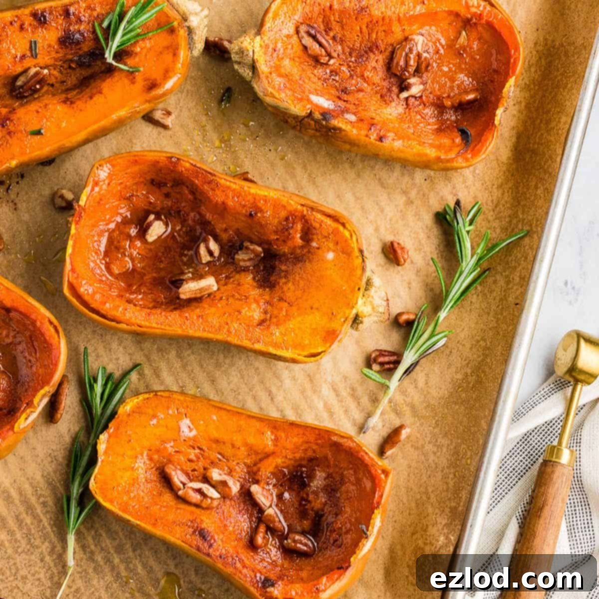 Sweet Maple Roasted Honeynut Squash Air Fryer Oven 2 Perfectly roasted honeynut squash halves on a sheet pan, garnished with fresh rosemary, toasted pecans, and a sprinkle of cinnamon, ready to serve.
