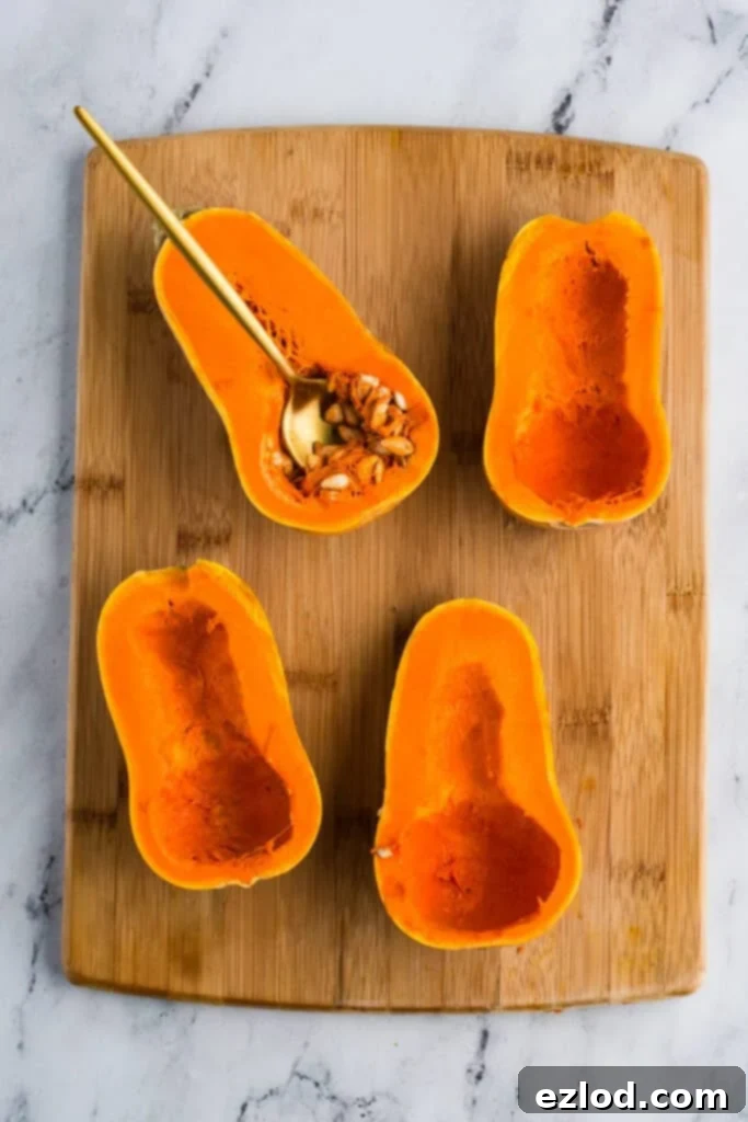 Sweet Maple Roasted Honeynut Squash Air Fryer Oven 5 Four honeynut squash halves meticulously arranged on a wooden cutting board, with their seeds completely scooped out, and a golden spoon holding a small pile of extracted seeds as an example.