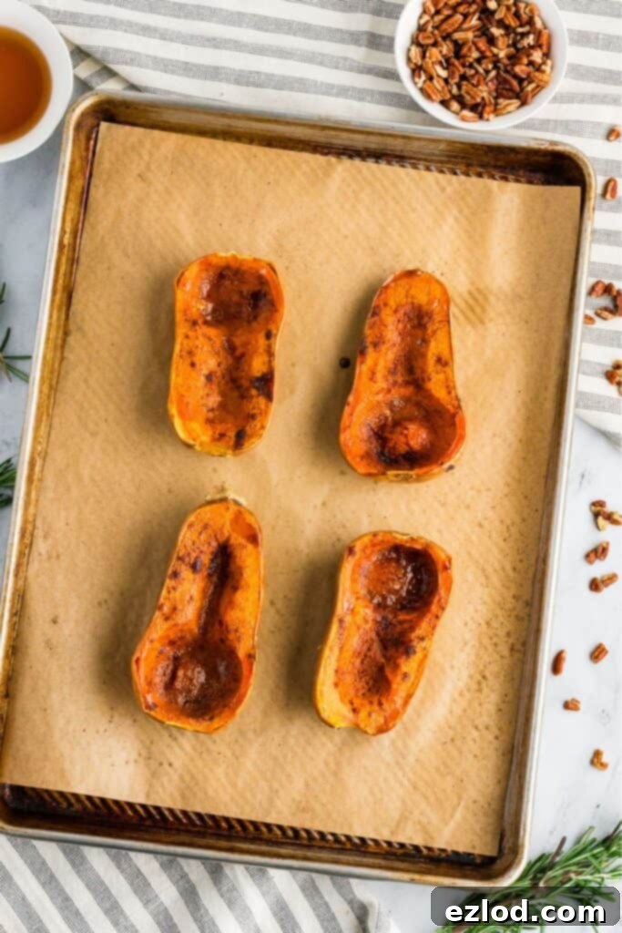 Sweet Maple Roasted Honeynut Squash Air Fryer Oven 8 Four exquisitely roasted honeynut squash halves glistening with caramelization, golden brown and tender, presented on a parchment-lined baking sheet, with a small bowl of toasted pecans in the soft-focus background.