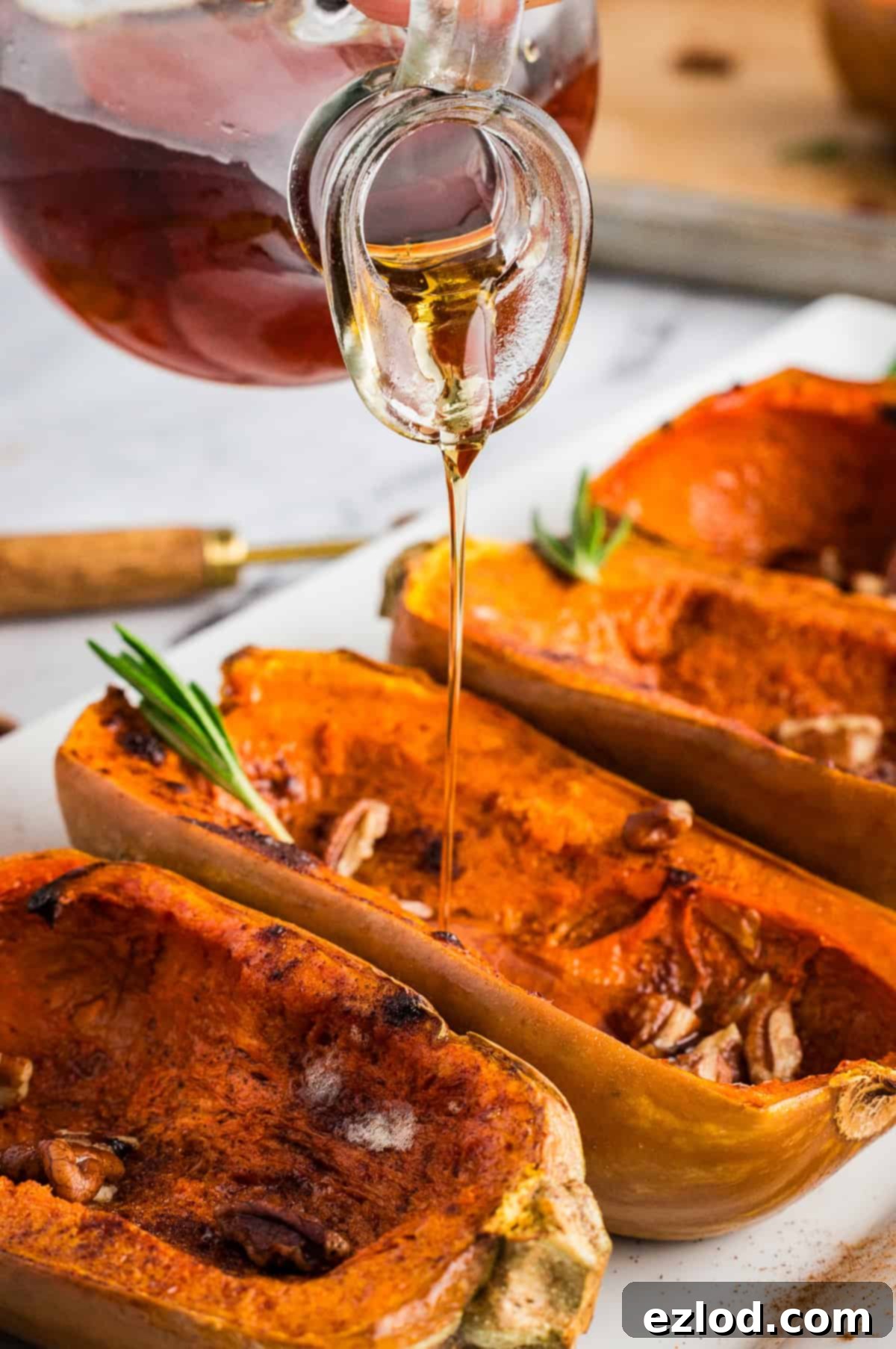 Sweet Maple Roasted Honeynut Squash Air Fryer Oven 9 A small jar of amber maple syrup being poured gracefully over a serving of roasted honeynut squash halves, enhancing their golden sheen.