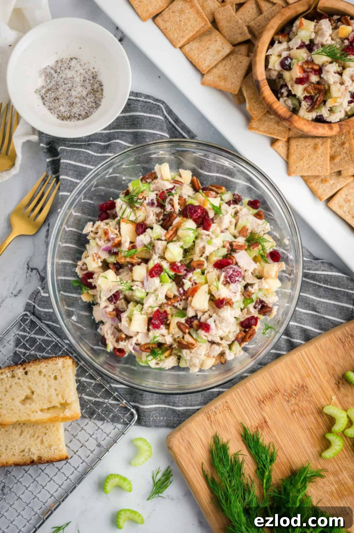 The finished, perfectly mixed turkey salad showcased beautifully in a transparent glass bowl, with distinct pieces of turkey, diced apple, cranberries, and pecans visible, all enveloped in a creamy dressing, resting on a white marble countertop. This image is repeated for visual appeal.