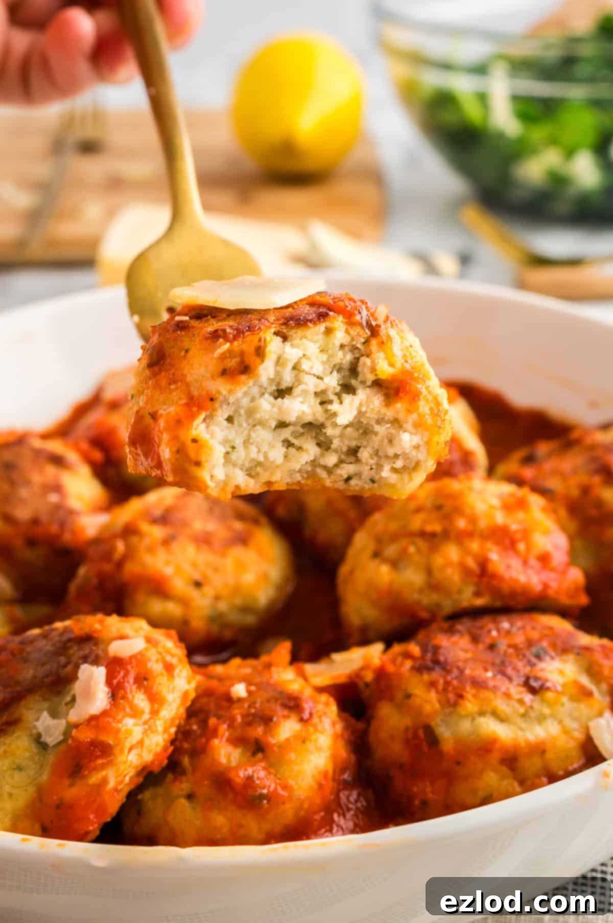 A fork holding a bitten into chicken meatballs.