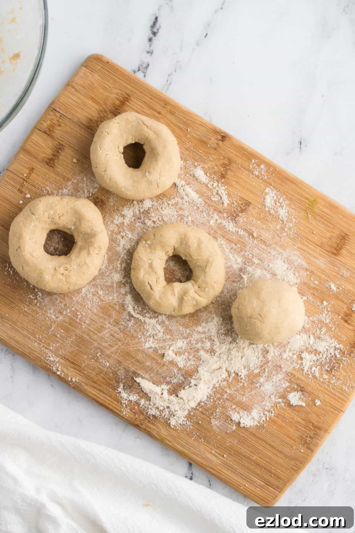 formed bagels on a cutting board before being cooked, shot from overhead