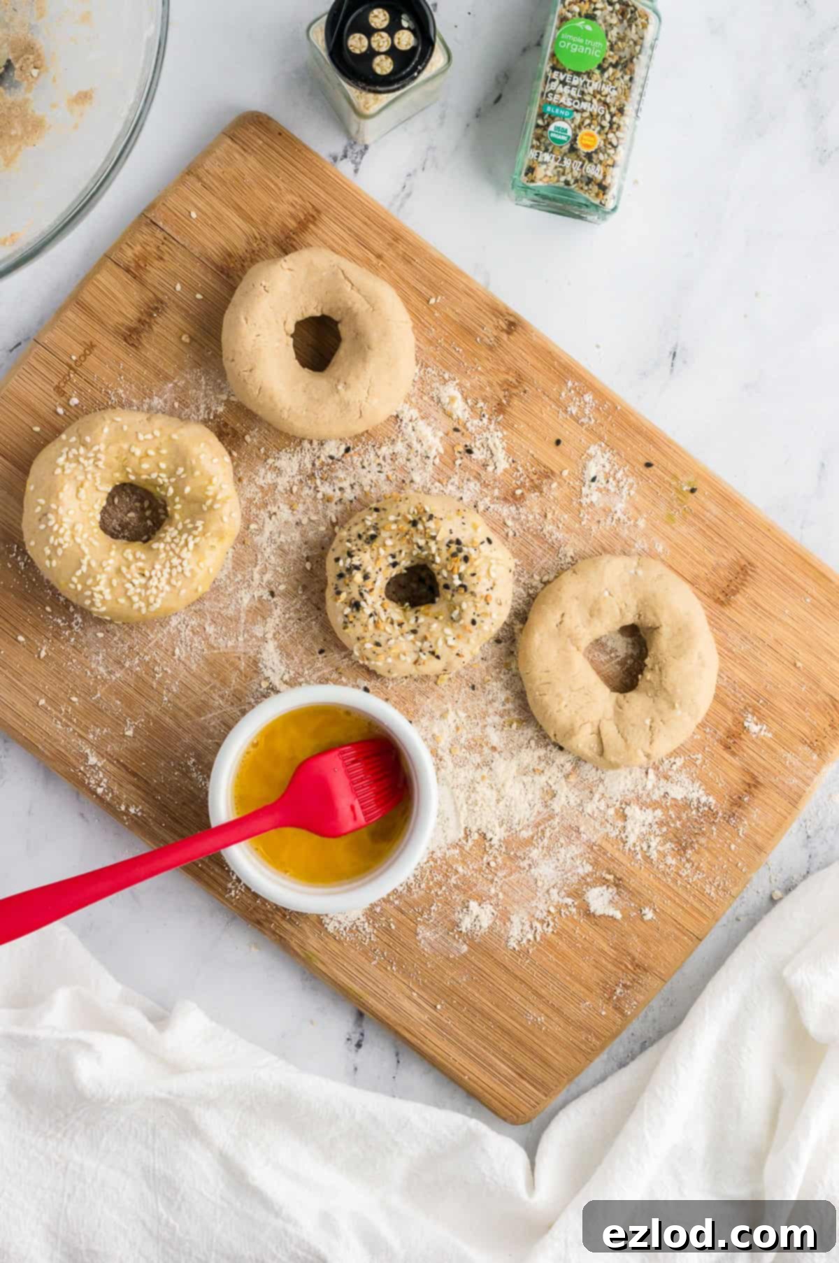 bagels before being cooked with an egg wash brushed on and toppings added, shot from overhead