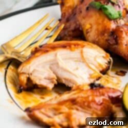 Glazed Sticky Chicken Thighs: Air Fried or Oven Baked 8 A piece of sticky air fryer chicken thigh on a white plate with a gold fork.