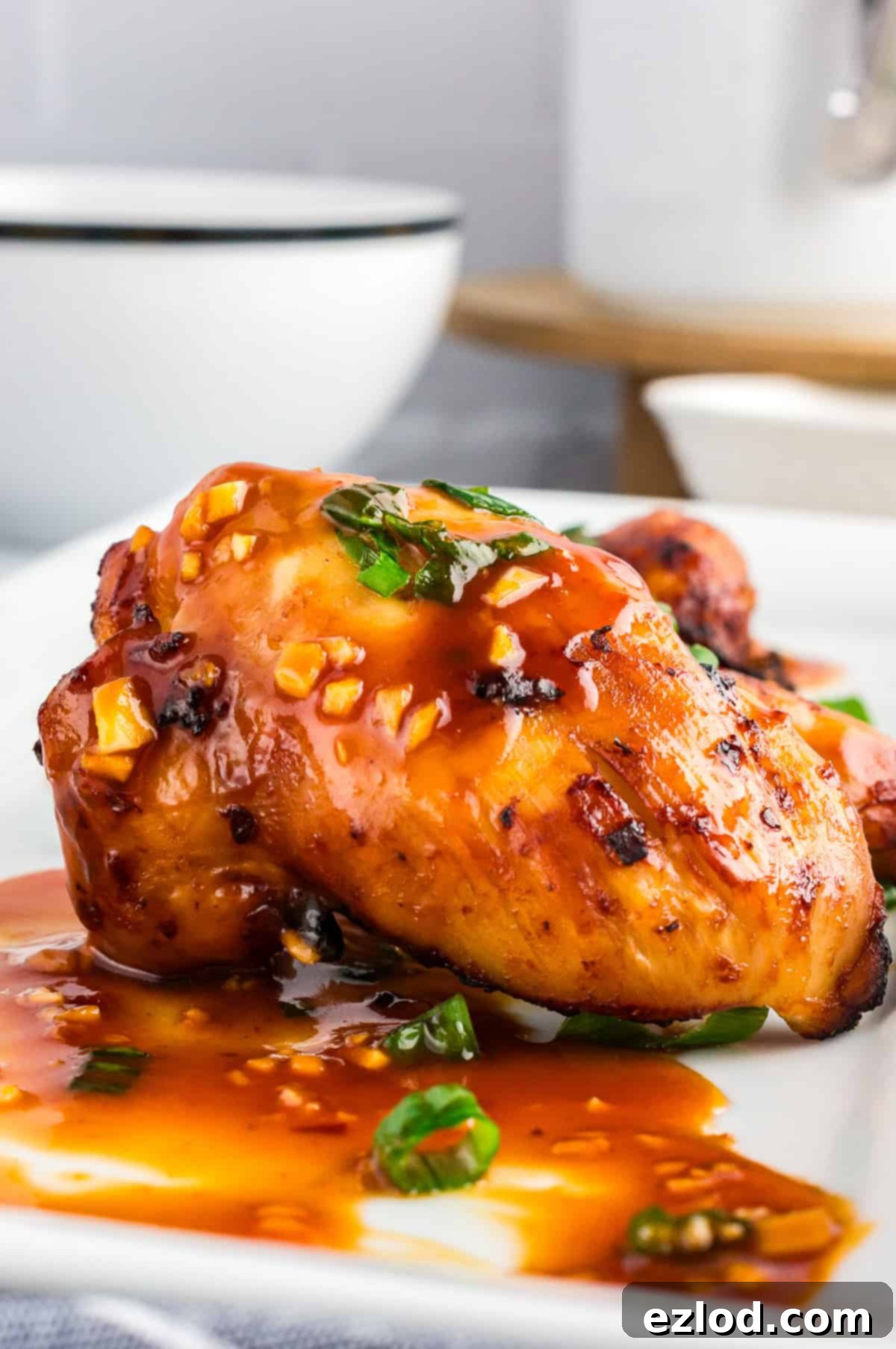 Glazed Sticky Chicken Thighs: Air Fried or Oven Baked 6 Close up shot of sticky air fryer chicken thighs on a white plate shot from the side.