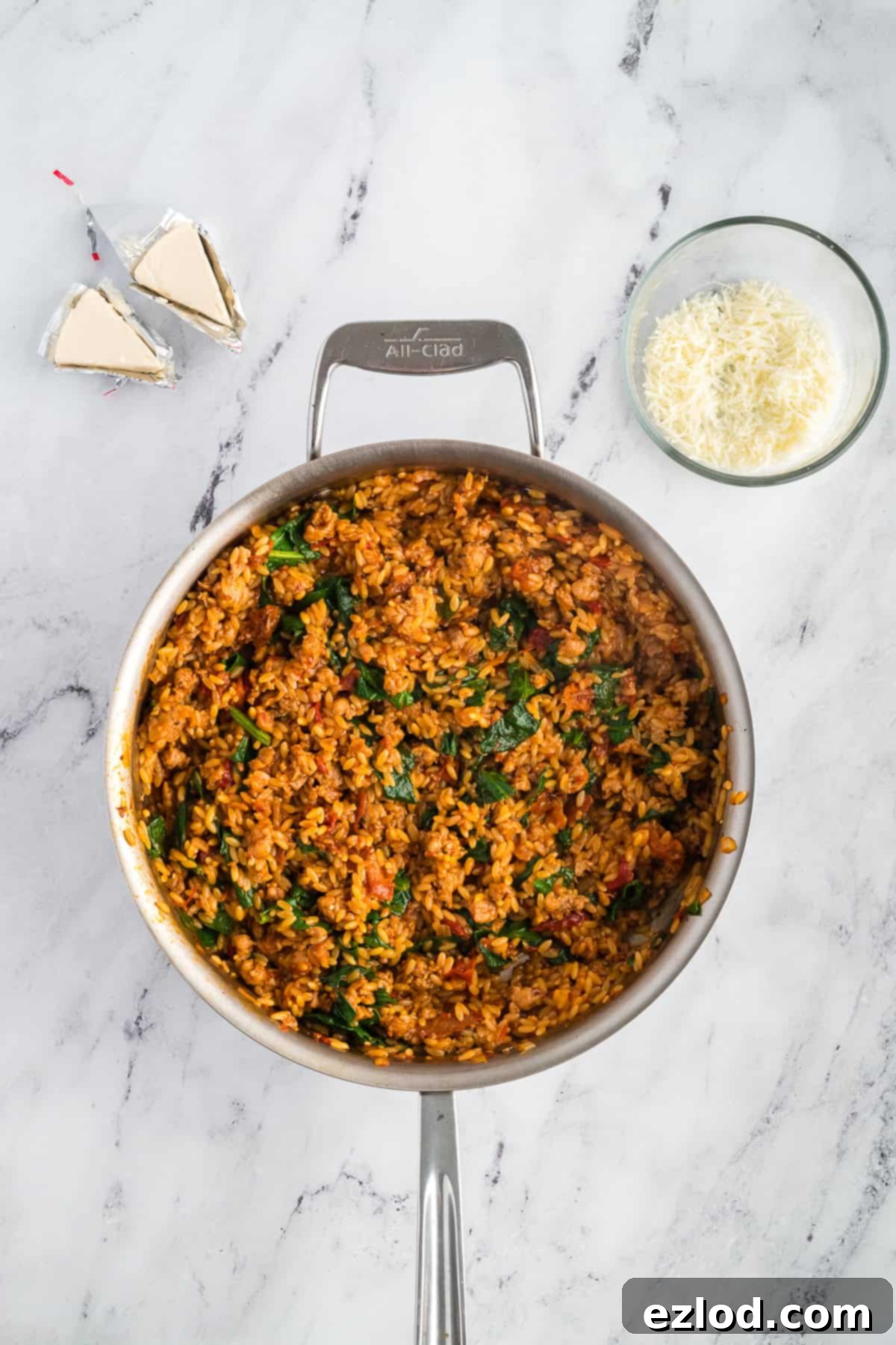 Marry Me Chicken Orzo in a skillet with wilted spinach mixed in, before cheese is added.
