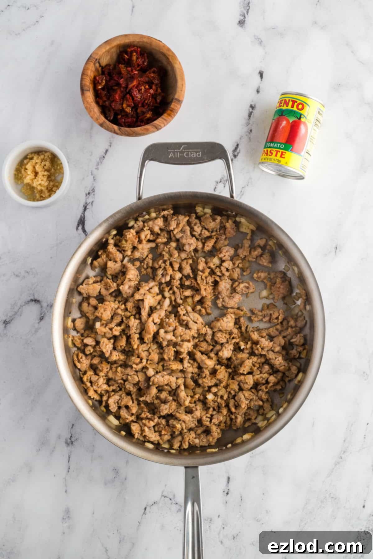 Cooked and crumbled chicken sausage mixed with sautéed onions in a large skillet.