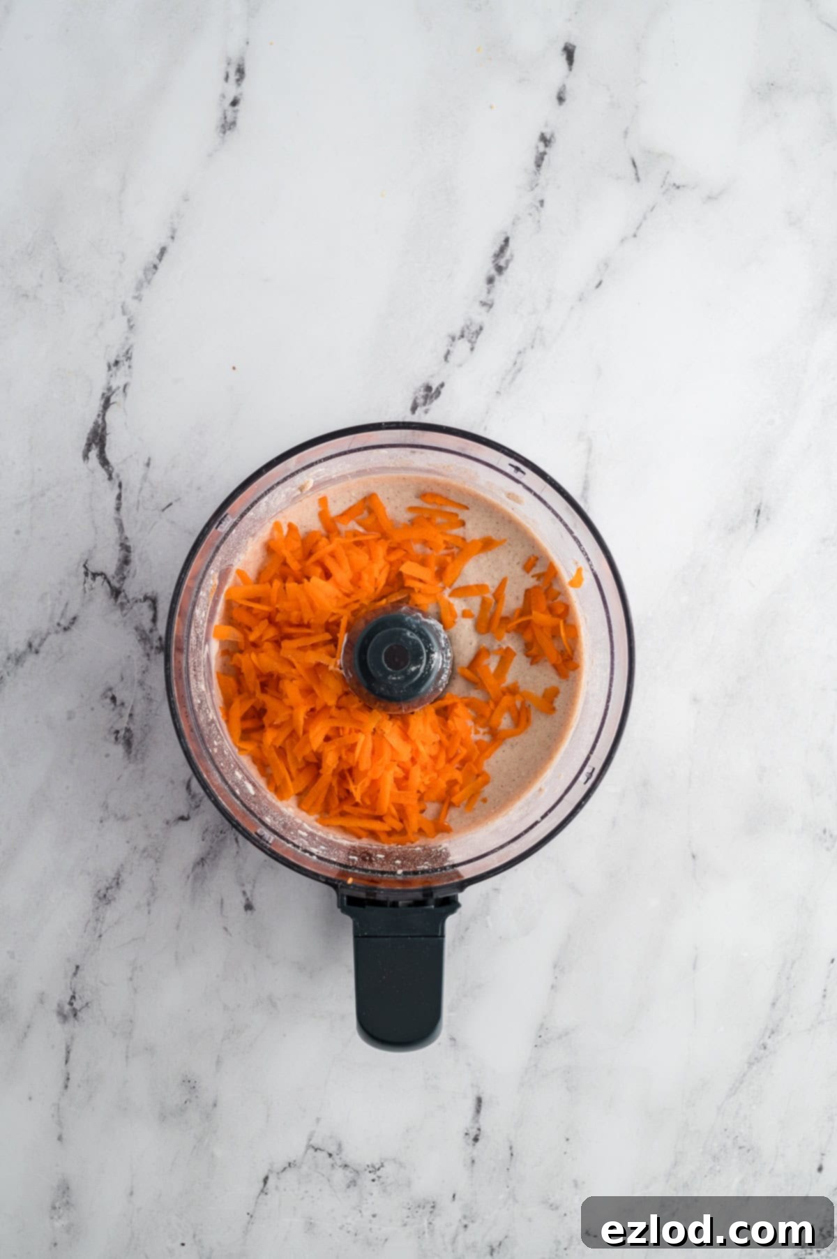 Carrots added to the food processor before being mixed in.