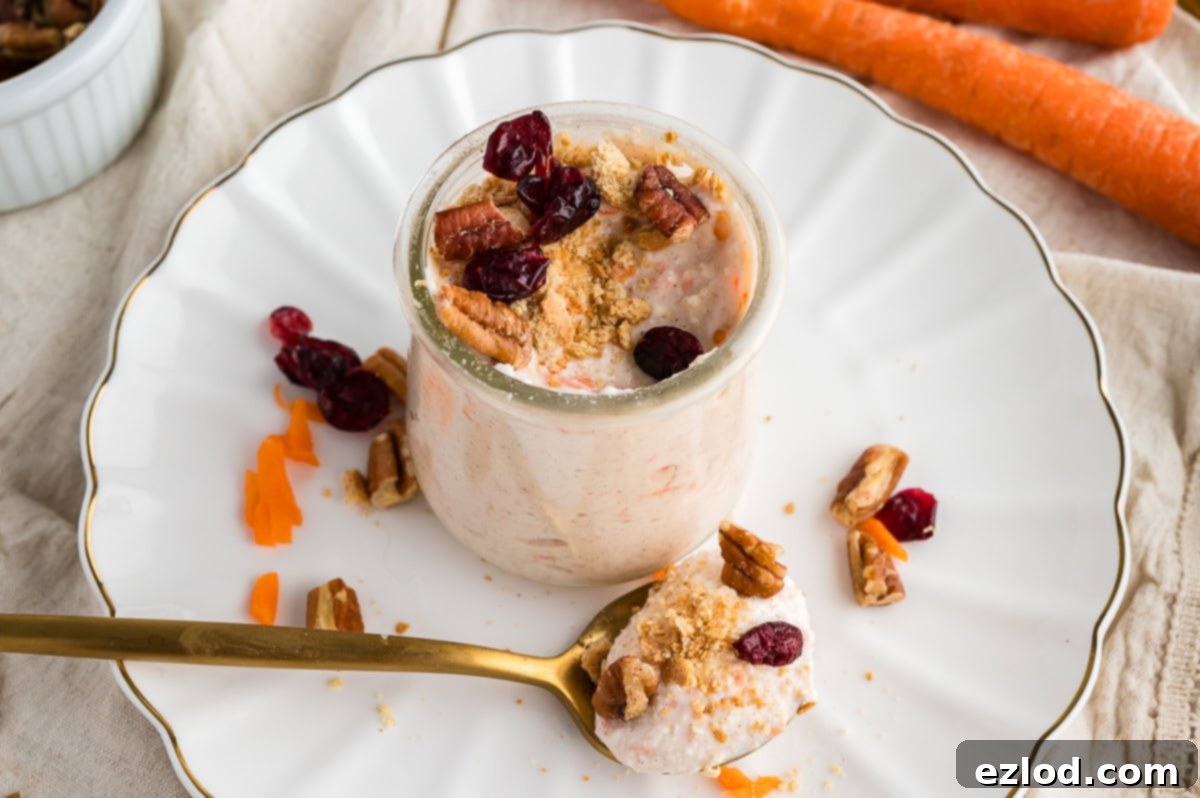 One carrot cake yogurt cup on a white plate with a gold spoon next to it.