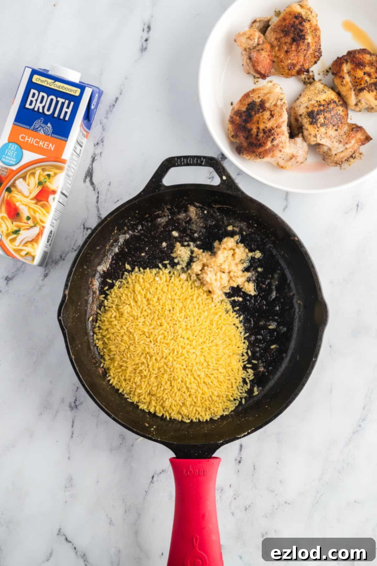 Your Go To One Pan Chicken Orzo 6 Orzo and minced garlic being toasted in a skillet before liquid is added.