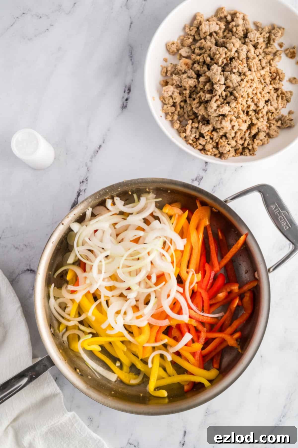 Thinly sliced onions and bell peppers ready to be sautéed in the same skillet.