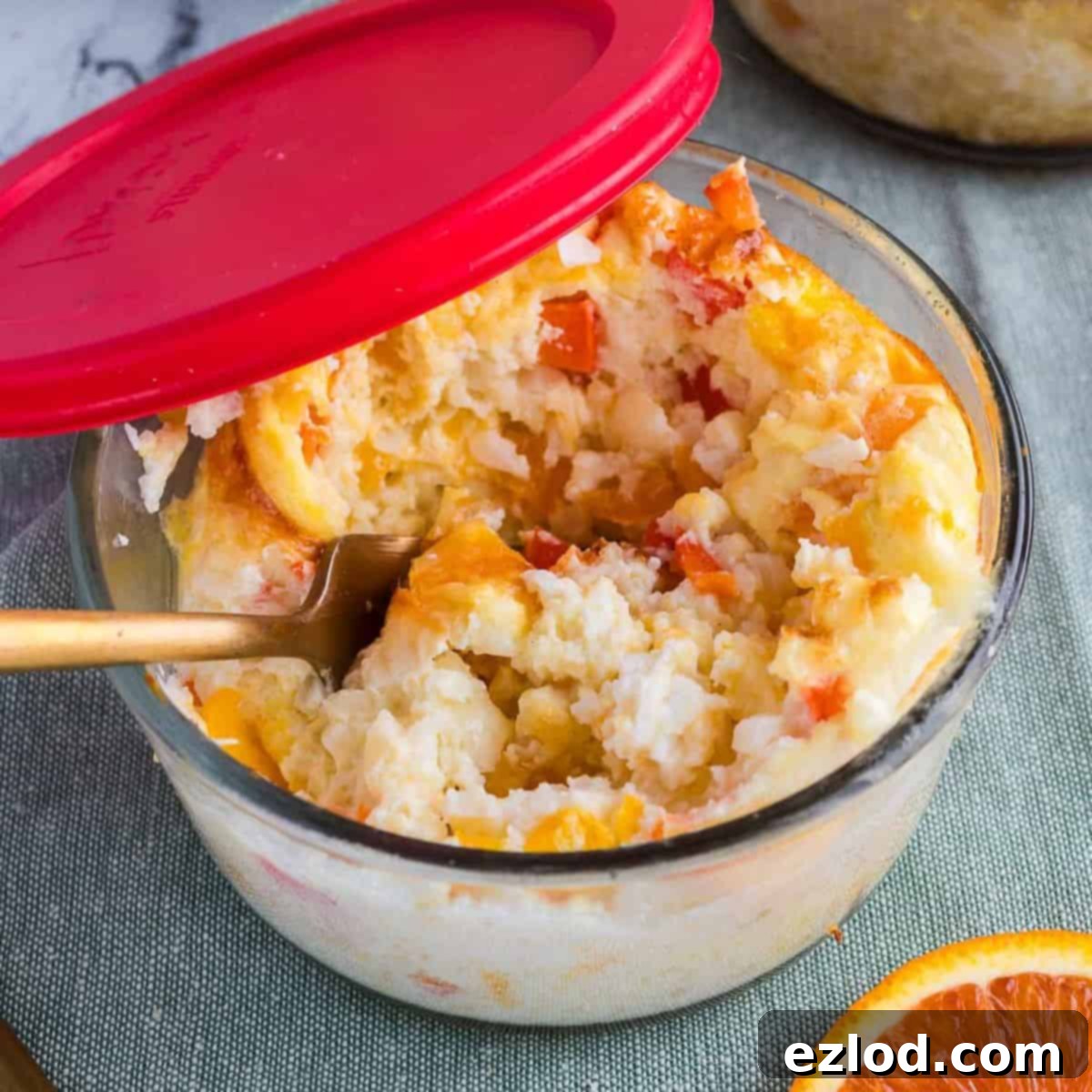 Breakfast meal prep bowls in a glass container with a red lid and a gold spoon inside.