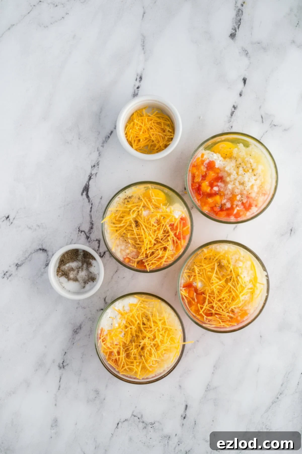 Breakfast bake ingredients in the individual cups before being cooked.