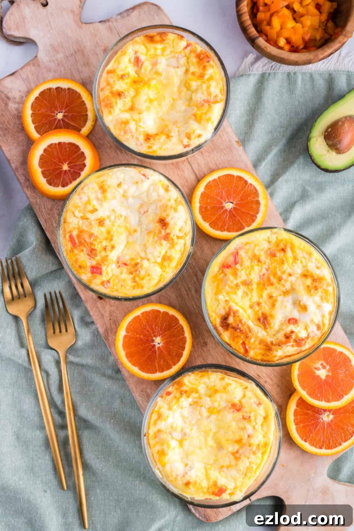 Baked breakfast bowls with citrus on a cutting board with gold forks.