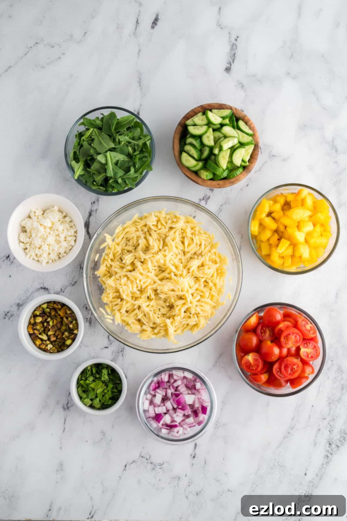 Ingredient for a peachy orzo salad arranged in clear bowls around the cooked orzo.