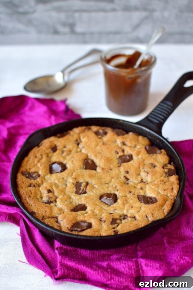 Delicious vegan Nutella stuffed chocolate chunk skookie cooling in a cast iron skillet, promising a rich and warm dessert.