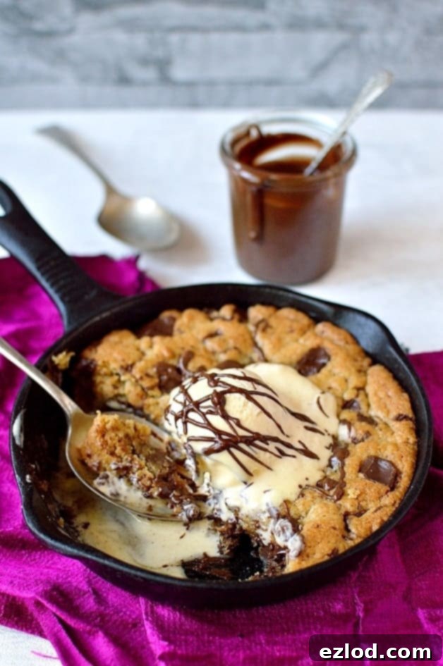 Rich and decadent Nutella stuffed chocolate chunk skillet cookie, drizzled with more Nutella and served with ice cream.