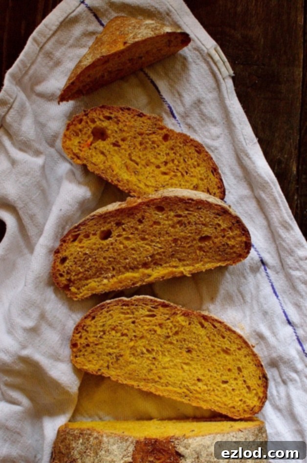 A rustic loaf of carrot and caraway seed bread, perfect for sandwiches, on a wooden board ready to be sliced.