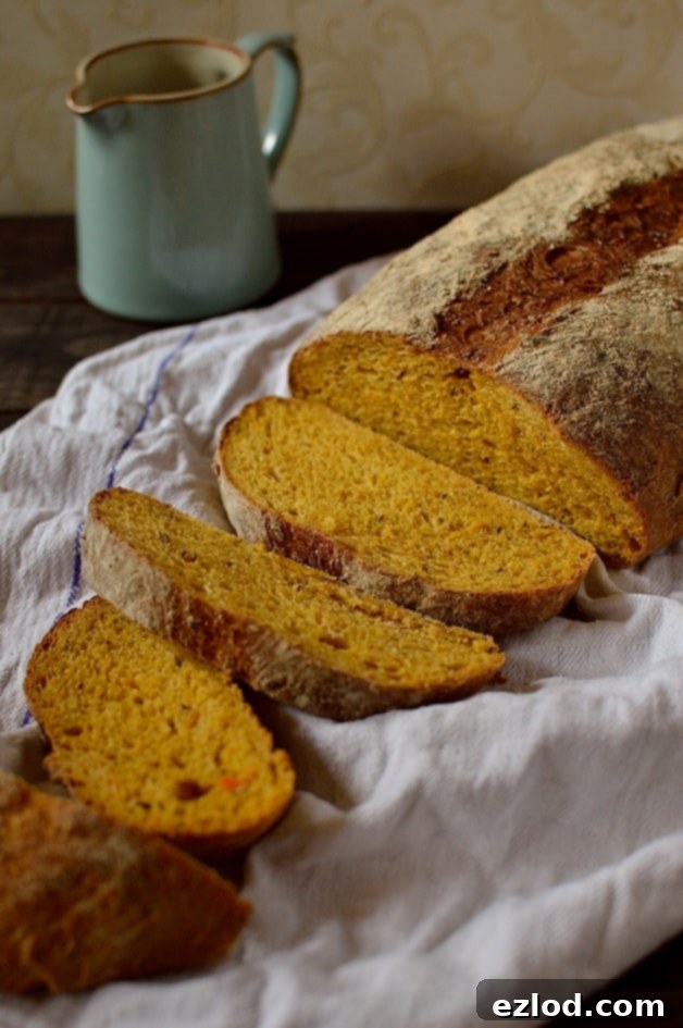A thick slice of homemade carrot and caraway seed sandwich bread with a beautiful orange hue and visible caraway seeds.